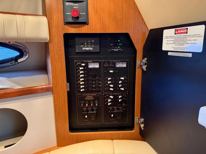 Slide: The Image of Electrical panel inside 2004 Cruisers Yachts 280 Express, featuring control switches and safety warnings. - 14