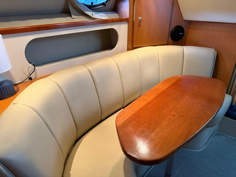 Slide: The Image of 2004 Cruisers Yachts 280 Express interior with beige seating and wooden table. - 21