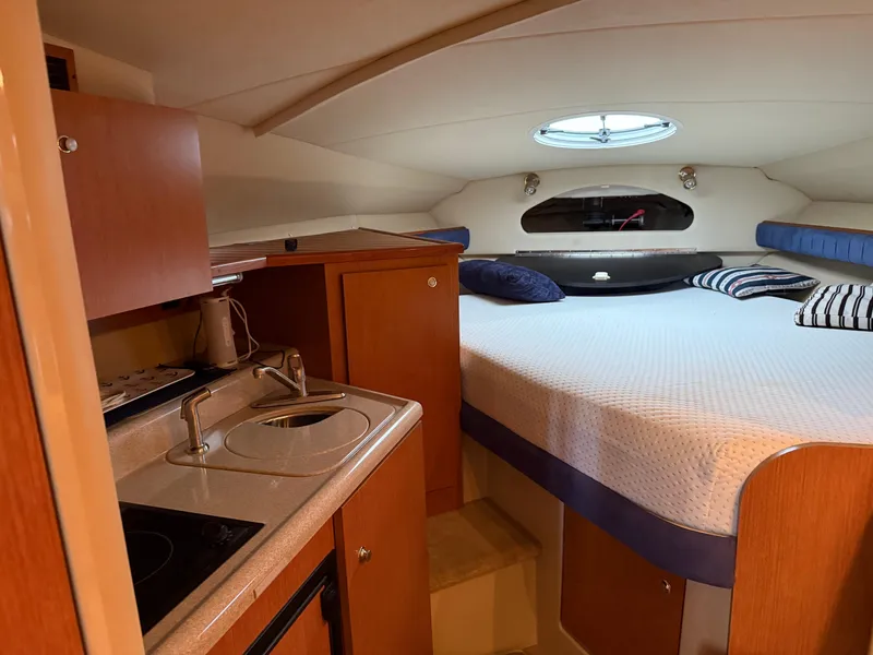 Slide: The Image of 2004 Cruisers Yachts 280 Express cabin interior with bed, kitchenette, and porthole. - 25