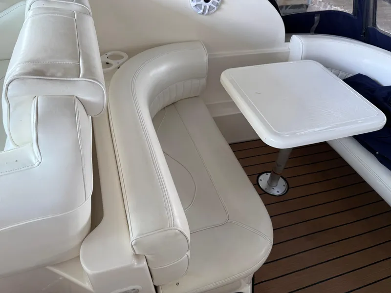 Slide: The Image of 2004 Cruisers Yachts 280 Express interior with white seating and table on wooden deck. - 31