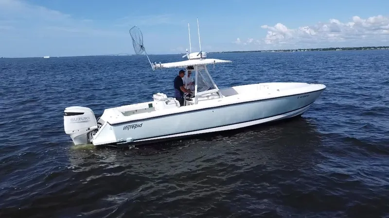Slide: The Image of 1998 Intrepid 327 Cuddy boat on open water with Suzuki outboard engine. - 11