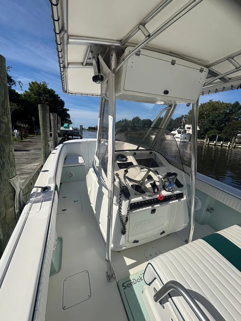Slide: The Image of 1998 Intrepid 327 Cuddy boat interior with steering console, docked by a scenic waterfront. - 15