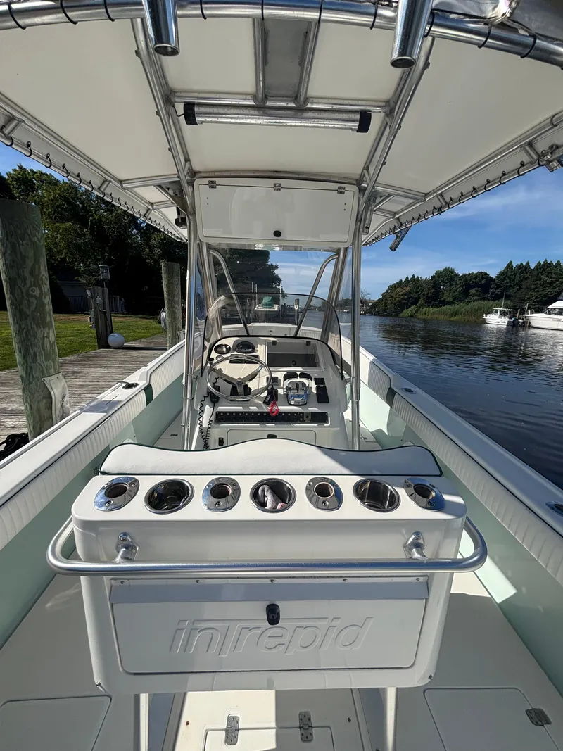 Slide: The Image of 1998 Intrepid 327 Cuddy boat interior with helm, rod holders, and canopy on a sunny day. - 17