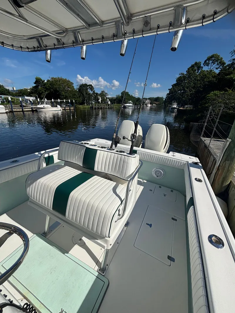 Slide: The Image of 1998 Intrepid 327 Cuddy boat interior with seating, docked on a calm river. - 19