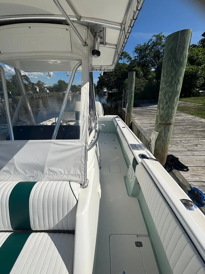 Slide: The Image of 1998 Intrepid 327 Cuddy boat docked, featuring white and green seating, under a clear blue sky. - 22