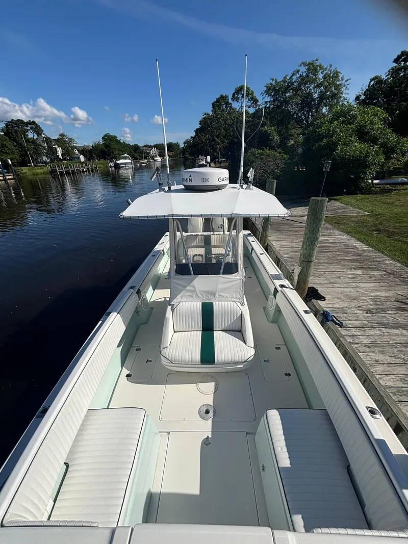 Slide: The Image of 1998 Intrepid 327 Cuddy boat docked by a serene river under a clear blue sky. - 23