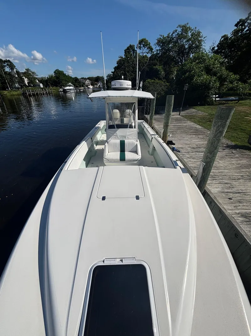 Slide: The Image of 1998 Intrepid 327 Cuddy boat docked by a serene waterfront. - 24