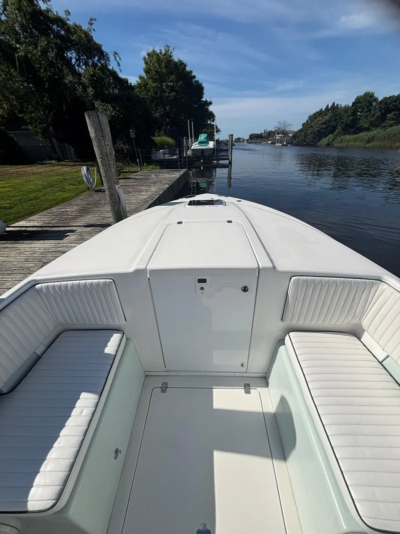Slide: The Image of 1998 Intrepid 327 Cuddy boat docked by a serene river under a clear blue sky. - 25