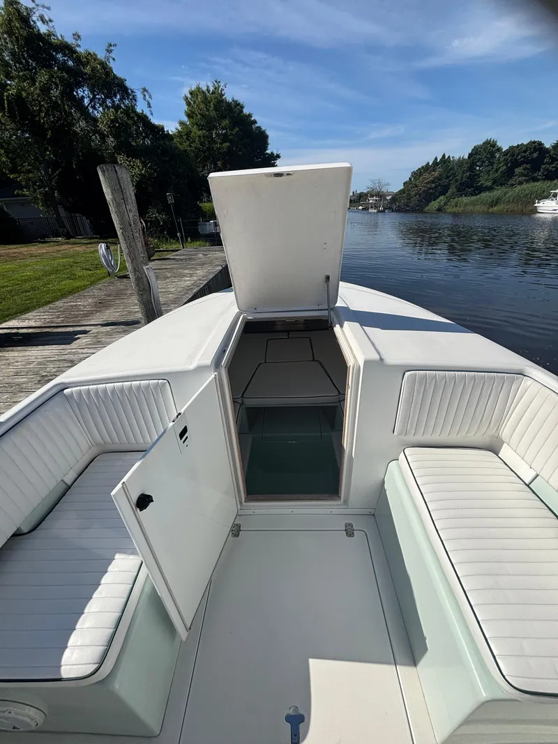Slide: The Image of 1998 Intrepid 327 Cuddy boat interior with open hatch, docked by a serene river. - 26