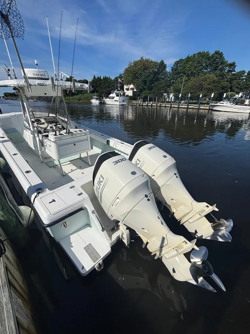 Slide: The Image of 1998 Intrepid 327 Cuddy boat with dual Suzuki engines docked by a calm waterfront. - 28