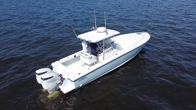Slide: The Image of 1998 Intrepid 327 Cuddy boat on open water, featuring dual Suzuki outboard engines. - 44