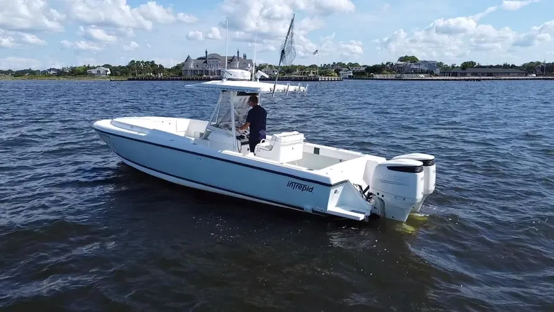 Slide: The Image of 1998 Intrepid 327 Cuddy boat on water, clear sky, coastal background. - 5