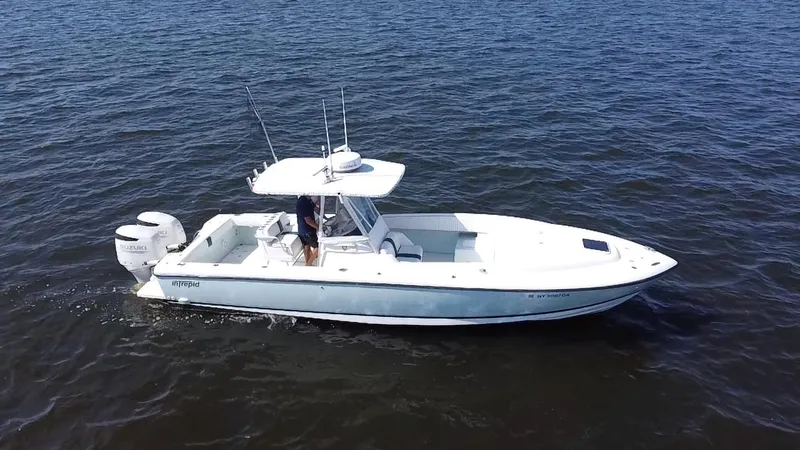 Slide: The Image of 1998 Intrepid 327 Cuddy boat cruising on open water, featuring dual outboard engines. - 6