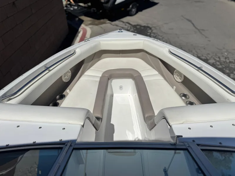 Slide: The Image of 2006 Cobalt 246 boat interior with white and beige seating, cup holders, and speakers. - 14