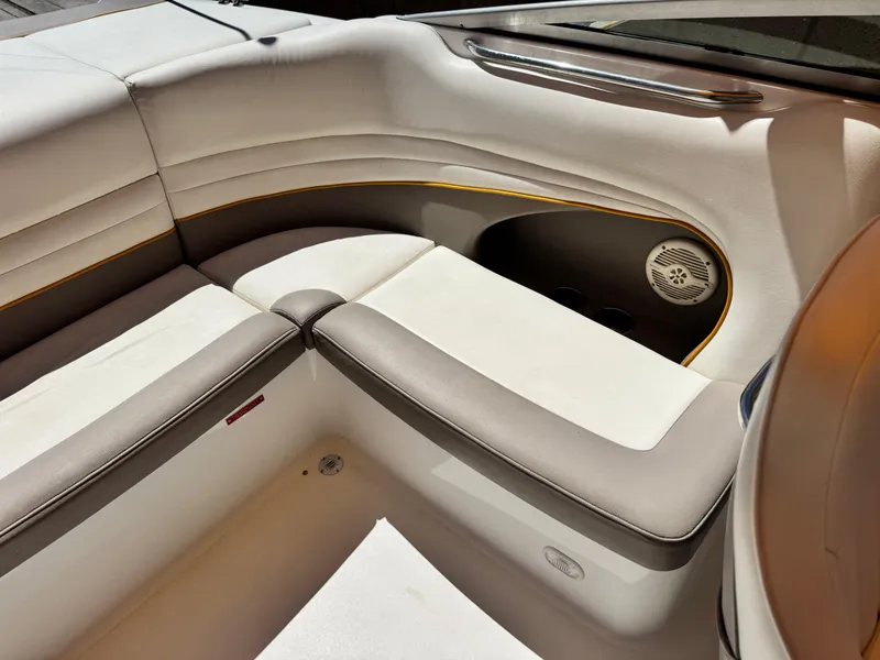 Slide: The Image of 2006 Cobalt 246 boat interior with white and gray seating, featuring a speaker and cup holders. - 19