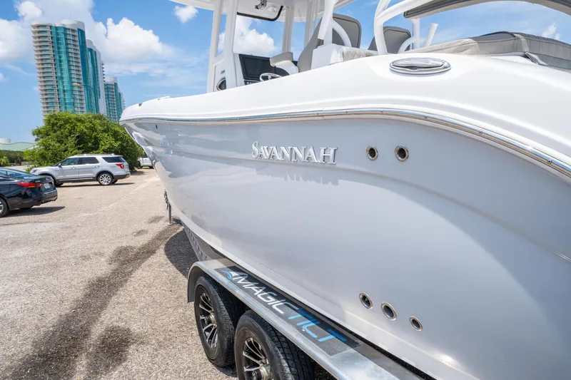 Slide: The Image of 2024 Savannah 2900 Offshore boat on trailer, parked near high-rise buildings. - 6