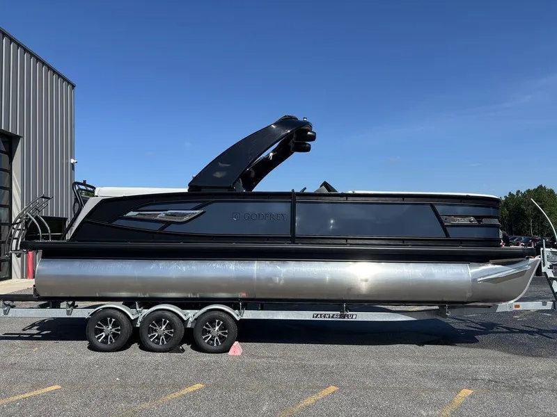 The Image of 2026 Godfrey AquaPatio 255 ULC pontoon boat on trailer, parked outdoors. - 1