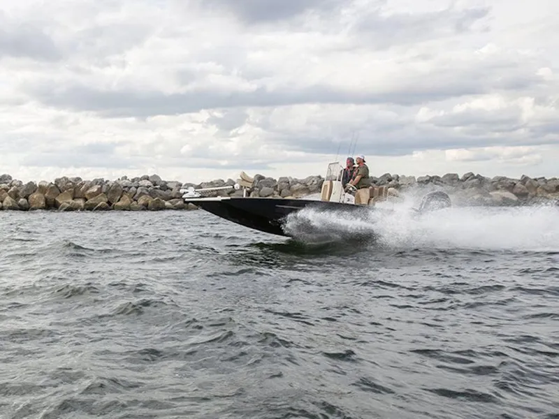 Slide: The Image of 2026 Xpress H22 Bay boat speeding on water near rocky shoreline. - 8
