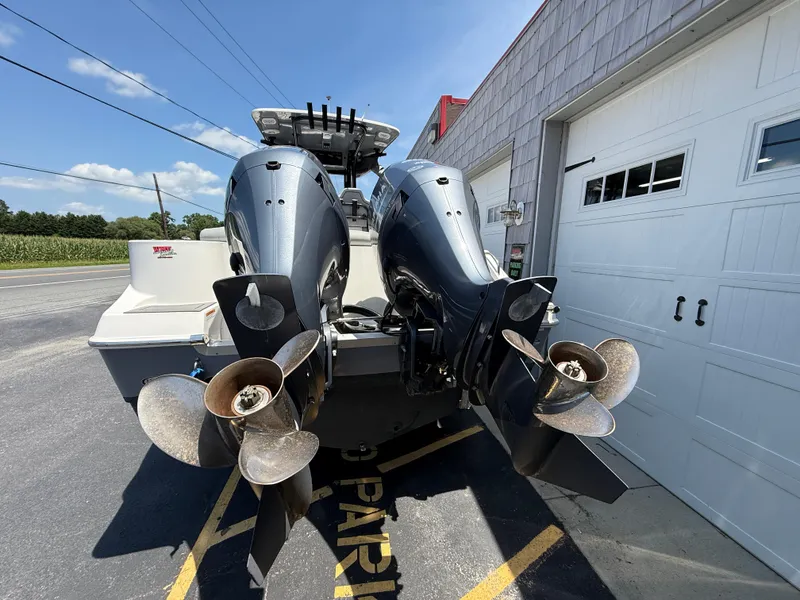 Slide: The Image of 2022 NauticStar 2602 Legacy boat with dual outboard motors in a parking area. - 12