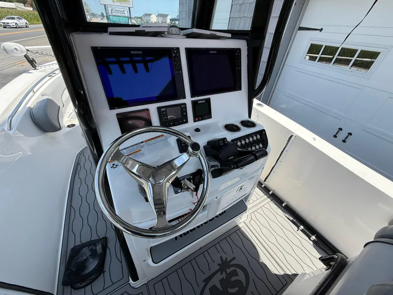 Slide: The Image of 2022 NauticStar 2602 Legacy boat helm with dual Simrad displays and stainless steel steering wheel. - 17