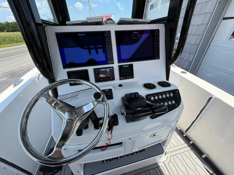 Slide: The Image of 2022 NauticStar 2602 Legacy boat helm with dual Simrad displays and steering wheel. - 18