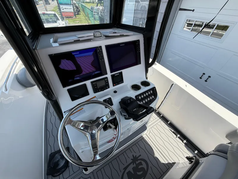Slide: The Image of 2022 NauticStar 2602 Legacy boat helm with dual Simrad displays and stainless steel steering wheel. - 19