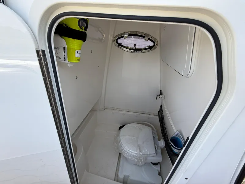 Slide: The Image of 2022 NauticStar 2602 Legacy boat interior with compact marine toilet and storage. - 21
