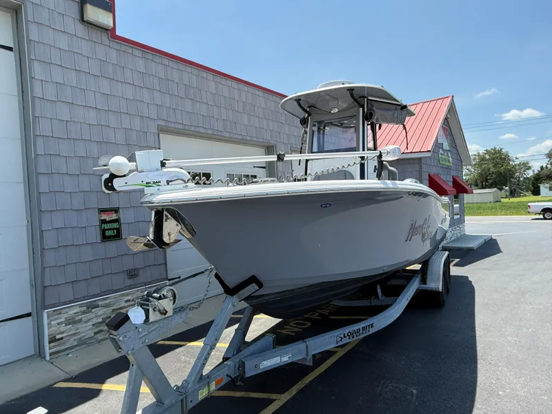 Slide: The Image of 2022 NauticStar 2602 Legacy boat on trailer, parked outside a building under clear skies. - 4