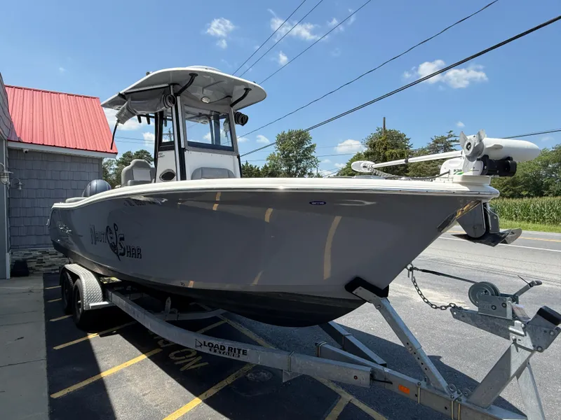 Slide: The Image of 2022 NauticStar 2602 Legacy boat on trailer, parked near a building with a red roof. - 8