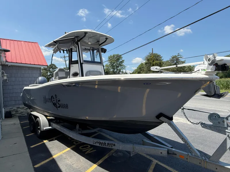 Slide: The Image of 2022 NauticStar 2602 Legacy boat on trailer, parked outdoors under clear sky. - 9