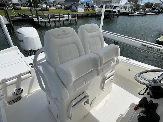 Slide: The Image of 2021 Regulator 26XO boat seats with helm, docked by waterfront homes. - 23