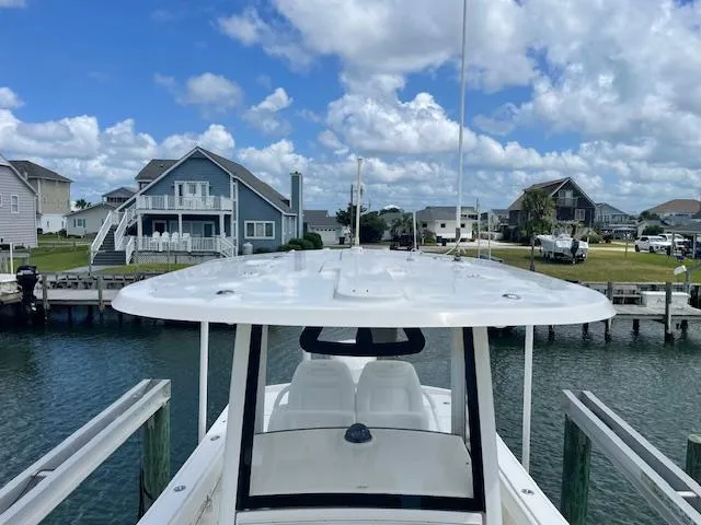 Slide: The Image of 2021 Regulator 26XO boat docked by waterfront homes under a blue sky. - 5