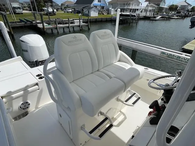 Slide: The Image of 2021 Regulator 26XO boat with dual white captain's seats, docked by the water. - 6
