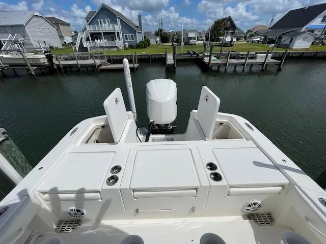 Slide: The Image of 2021 Regulator 26XO boat docked, showcasing spacious deck and seating, with waterfront homes in background. - 9