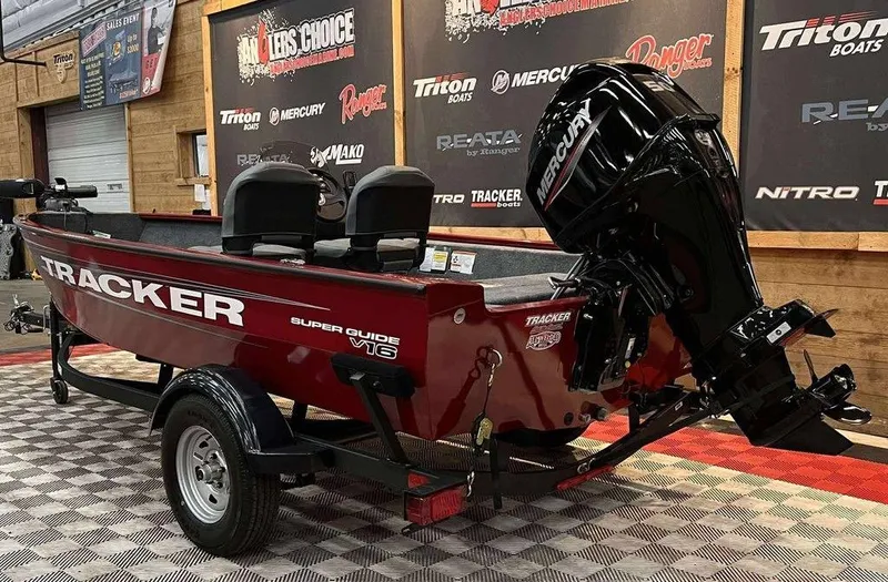 Slide: The Image of 2026 Tracker Super Guide V-16 SC boat with Mercury engine on display indoors. - 3