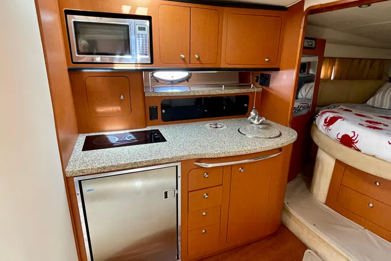 Slide: The Image of 2005 Chaparral Signature 350 yacht interior with kitchenette, featuring microwave, stove, and compact fridge. - 23