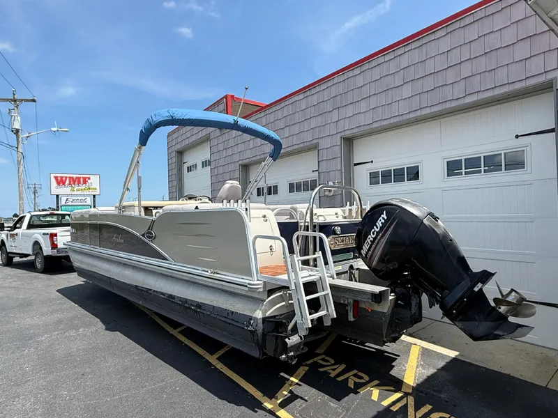 Slide: The Image of 2014 Avalon 2585 Catalina Bar Tri Toon boat with Mercury engine parked outside a garage. - 8