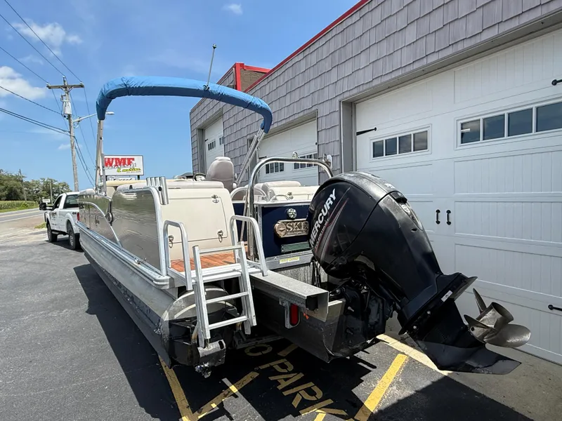 Slide: The Image of 2014 Avalon 2585 Catalina Bar pontoon boat with Mercury outboard motor, parked outside garage. - 9