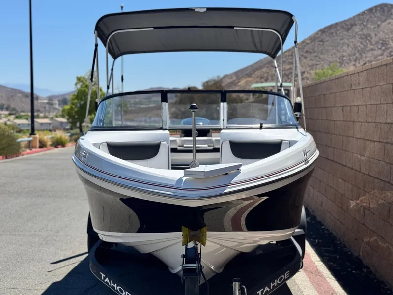 Slide: The Image of 2019 Tracker Tahoe 450 TF boat with canopy, parked on a sunny day. - 2
