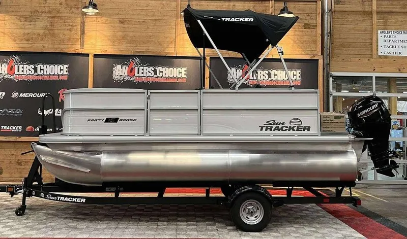 The Image of 2026 Sun Tracker PARTY BARGE® 16 DLX pontoon boat displayed indoors on a trailer. - 1