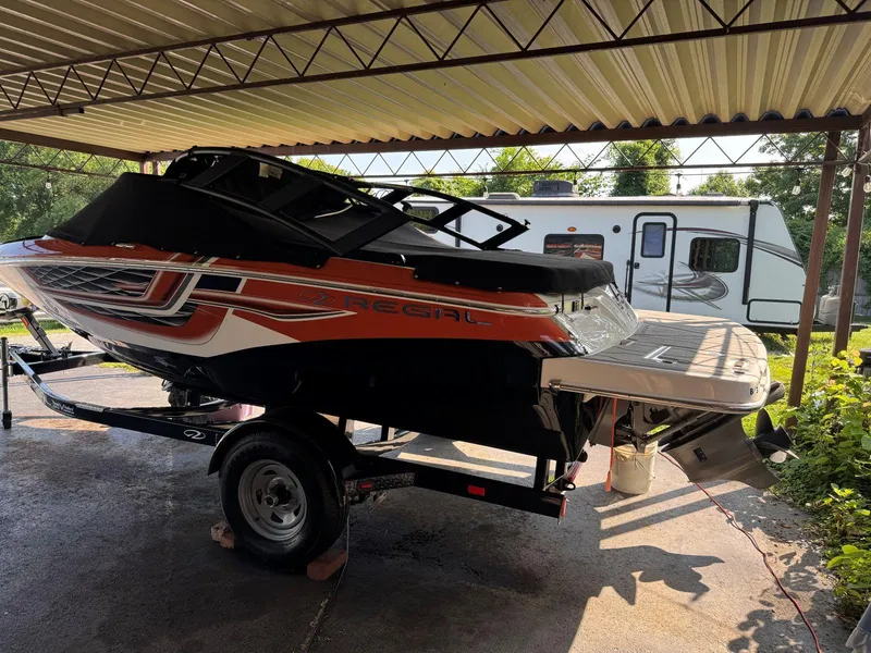 Slide: The Image of 2018 Regal 1900 ESX Bowrider boat on trailer under a metal canopy. - 2