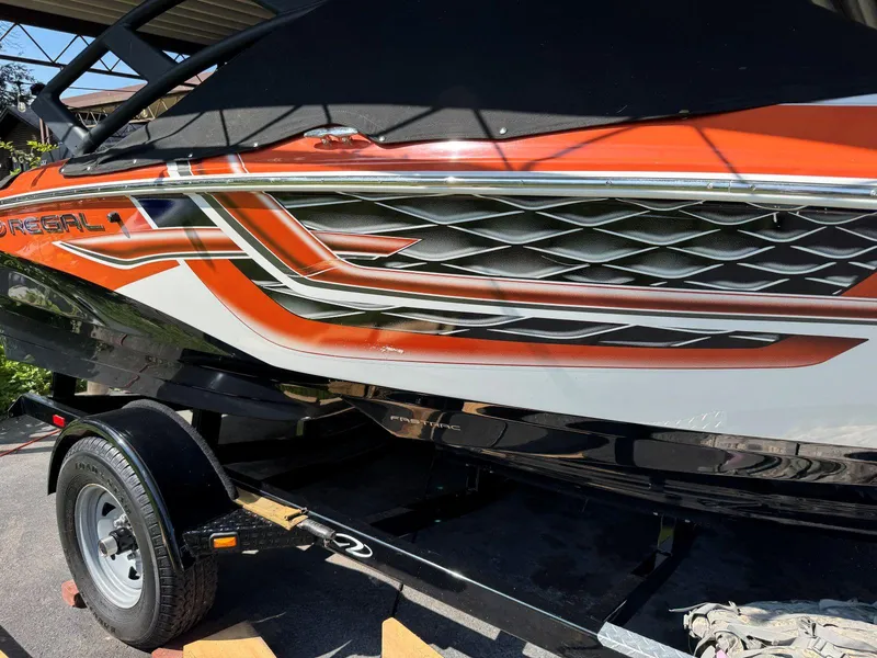 Slide: The Image of 2018 Regal 1900 ESX Bowrider with vibrant orange and black design on trailer. - 24