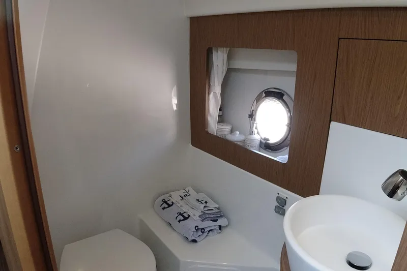 Slide: The Image of 2016 Beneteau GT35 bathroom with porthole, sink, and nautical-themed towels. - 24