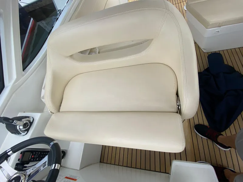 Slide: The Image of 2016 Beneteau GT35 helm seat with white upholstery and teak flooring. - 18
