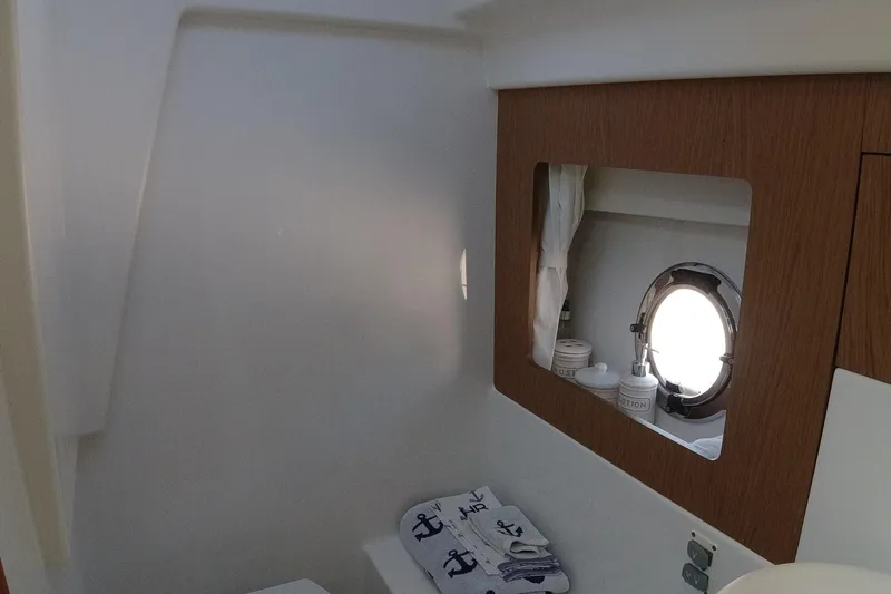 Slide: The Image of Beneteau GT35 2016 model bathroom with porthole, mirror, and nautical-themed towel. - 25