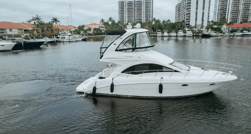 Slide: The Image of 2010 Sea Ray 390 Sedan Bridge yacht cruising in a marina with waterfront buildings. - 3