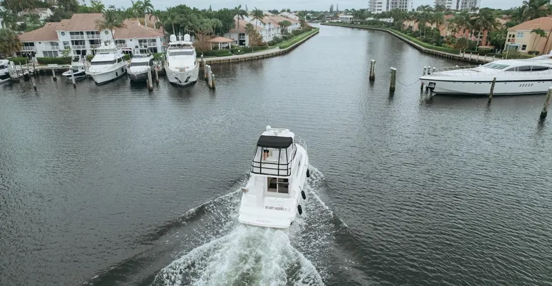 Slide: The Image of 2010 Sea Ray 390 Sedan Bridge cruising through a scenic canal with luxury yachts. - 8