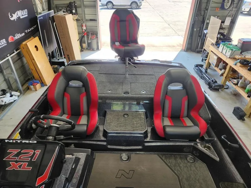 Slide: The Image of 2026 Nitro Z21 XL Pro boat interior with red and gray seats in a garage setting. - 12