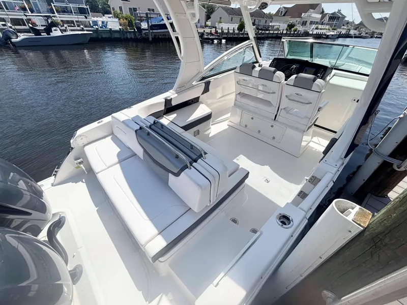 Slide: The Image of 2020 Chaparral 300 OSX boat interior with seating and helm, docked by the water. - 18