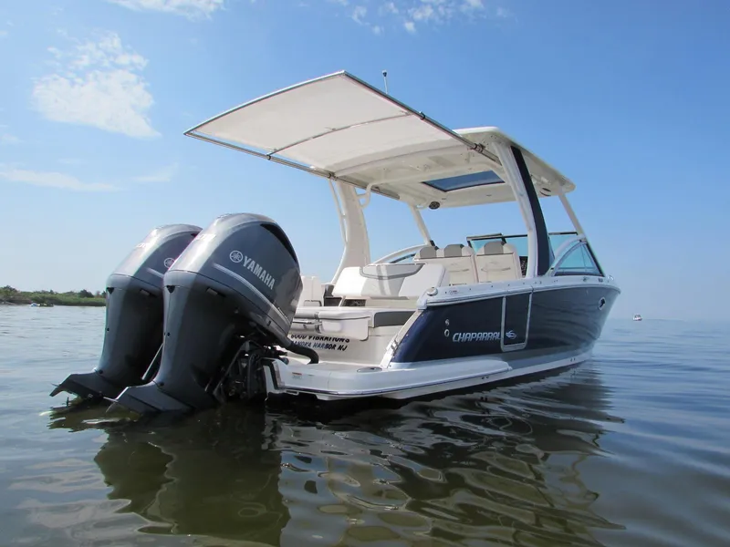 Slide: The Image of 2020 Chaparral 300 OSX boat with Yamaha engines on calm water under blue sky. - 2